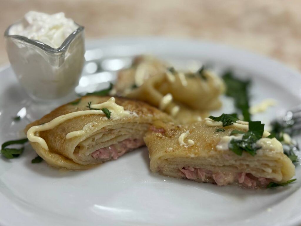 В Боровлянах подают блины с начинкой и сметаной, в которой стоит ложка